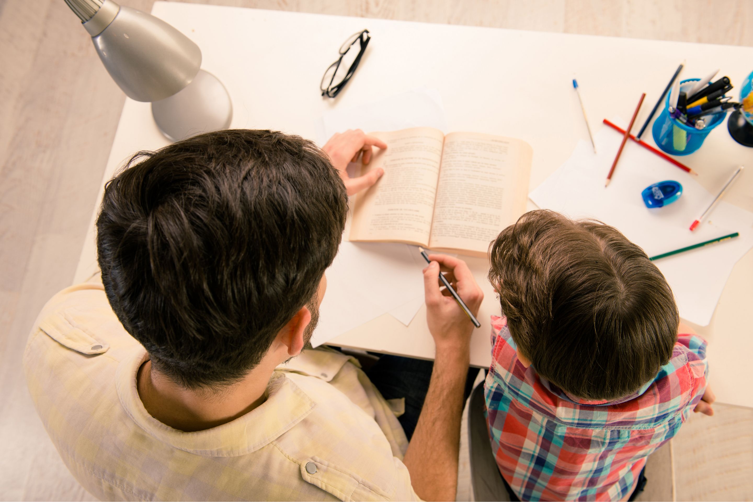 top view of dad helping kid learn at table